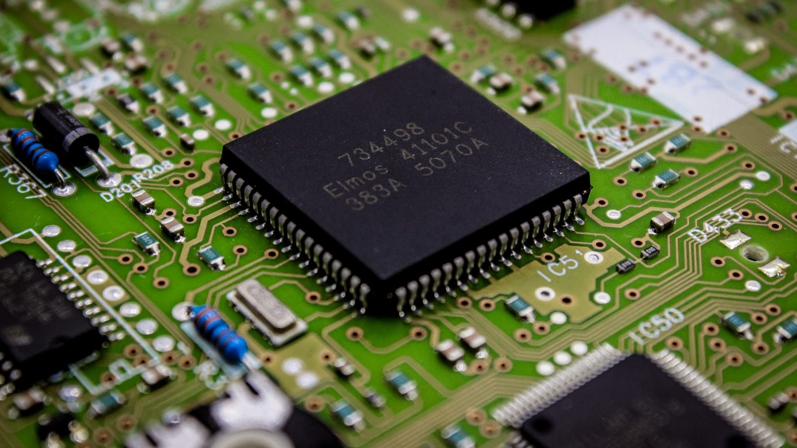 Macro photograph of a microchip on a green printed circuit board
